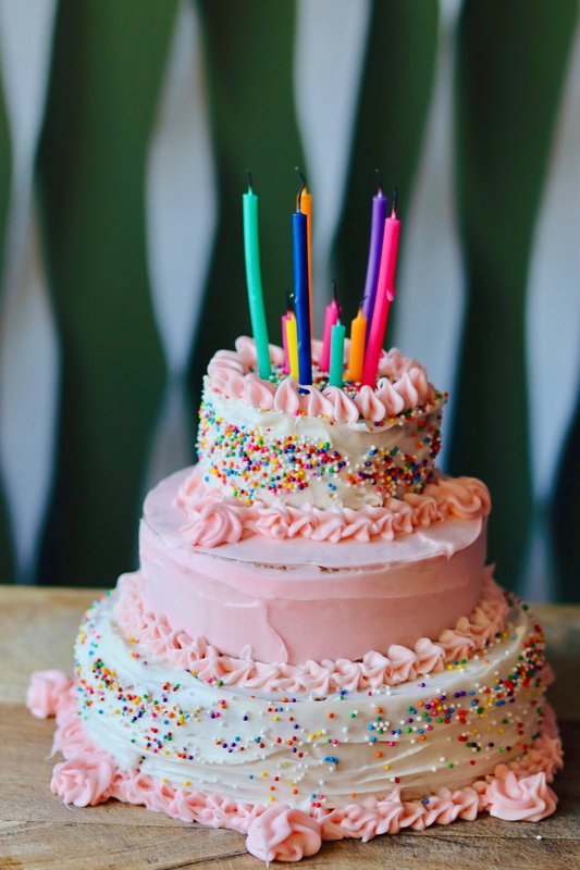 White birthday cake with pink icing and sprinkles
